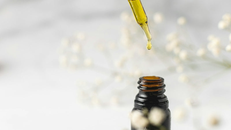 Flacon ambre avec pipette et fleurs blanches - guide lubrifiants